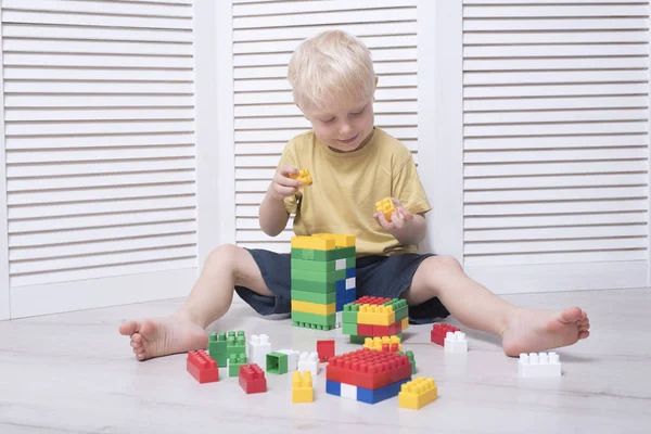 Küçük sarışın çocuk renkli tasarımcı yapıyor.