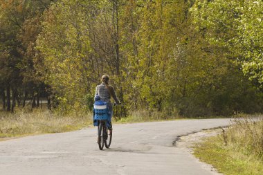Anne ve oğlu sonbahar yolda bir bisiklet sürme vardır. Arkadan Görünüm.