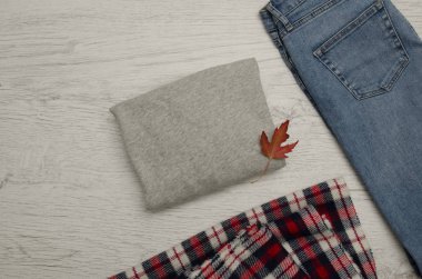 Gri kazak, kot, eşarp ve sonbahar yaprakları. Moda kavramı