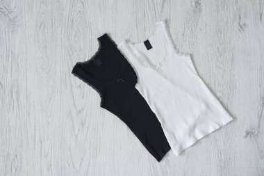 Ahşap arka plan üzerinde siyah ve beyaz kolsuz bluz. Moda kavramı