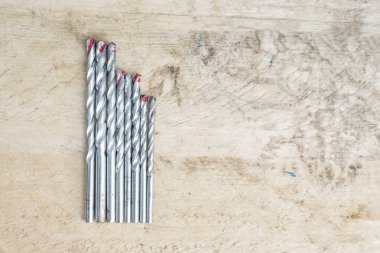 Ahşap arka plan üzerinde farklı boyutta matkaplar kümesi. Üstten görünüm