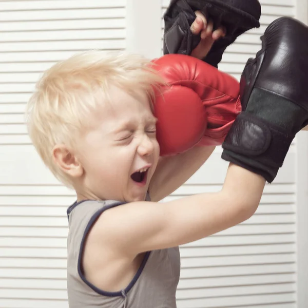 金髪の少年は 赤い手袋で手でボクシングします 顔で吹く — ストック写真