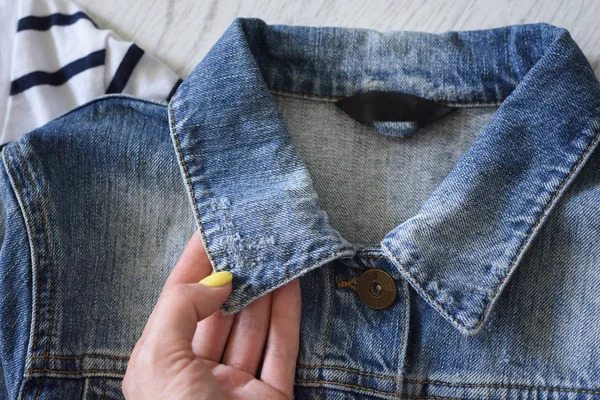 Collar of a denim jacket  in female hand. Fashionable concept
