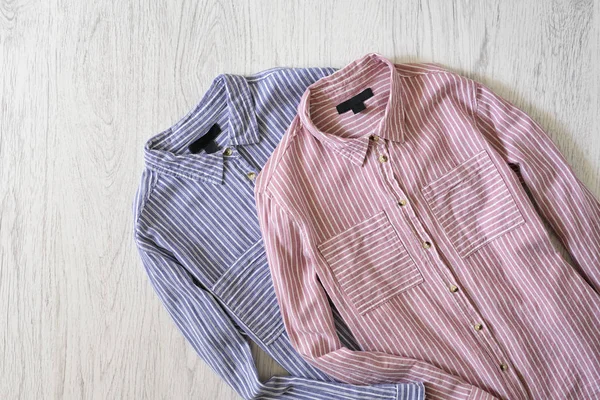 Pink and blue striped shirts on wooden background. Fashionable concept
