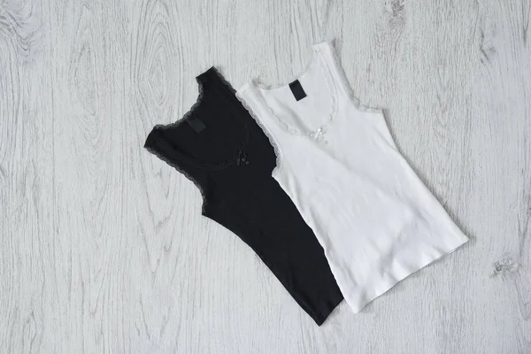 Ahşap arka plan üzerinde siyah ve beyaz kolsuz bluz. Moda kavramı