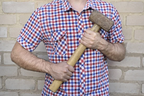 Man with a hammer, on the brick wall background. Working concept