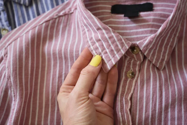 Collar of a pink shirt in female hand. Fashionable concept