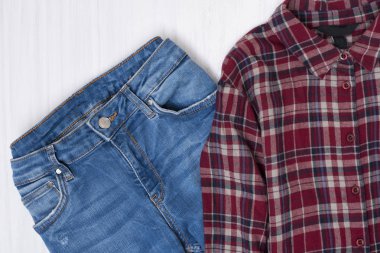 Mavi jeans ve ahşap arka plan üzerinde kırmızı kareli gömlek. Moda kavramı