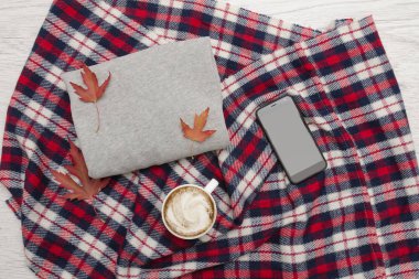 Gri kazak, ekose, fincan kahve ve akıllı telefon. Sonbahar yaprakları. Moda kavramı