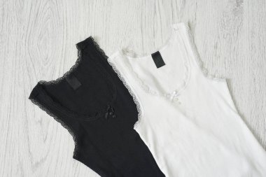 Ahşap arka plan üzerinde siyah ve beyaz kolsuz bluz. Moda kavramı