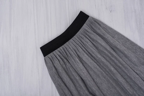 Gray pleated skirt on wooden background. Fashionable concept. Close up