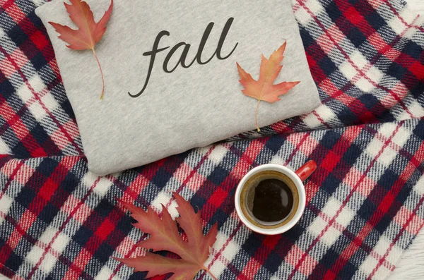 Gray sweater, plaid and coffee mug. Autumn leaves. Fashionable concept