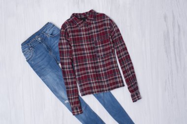 Mavi jeans ve ahşap arka plan üzerinde kırmızı kareli gömlek. Moda kavramı