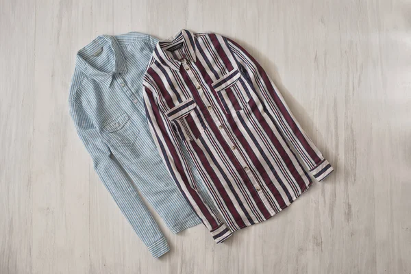 Two striped shirts on wooden background. Fashionable concept