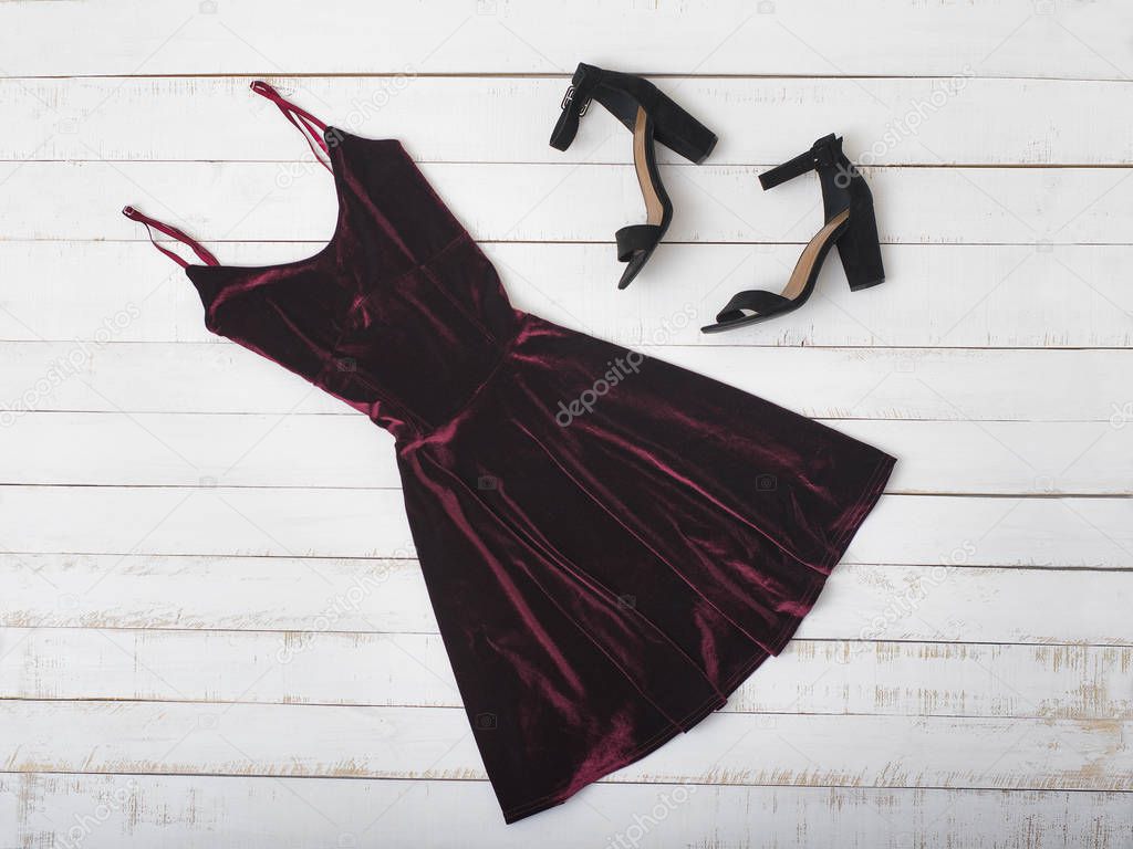 Velvet burgundy dress and shoes on wooden background. Fashionable concept