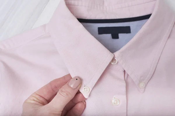 Collar of pink shirt in female hand. Fashionable concept