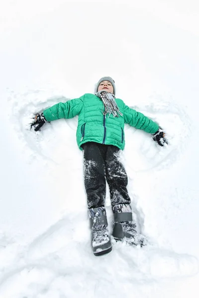 Хлопчик Капелюсі Шарфі Зеленому Піджаку Лежить Снігу Робить Ангела Портрет — стокове фото