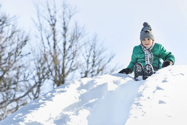 Хлопчик Капелюсі Шарфі Зеленому Піджаку Ковзає Снігової Гірки Спині Зимовий — стокове фото