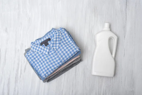 Stack of folded shirts and detergent bottle. Top view