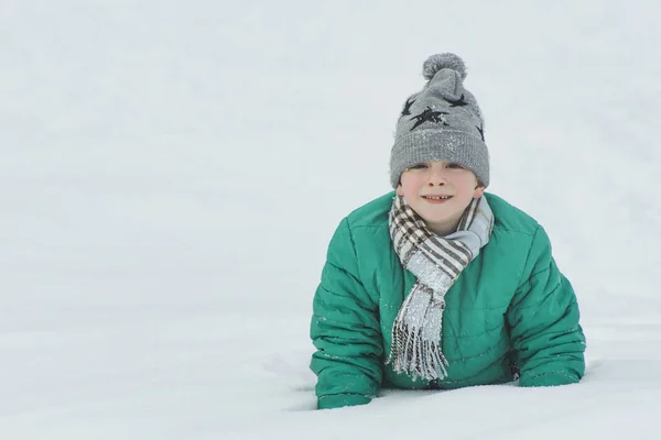 Αγόρι Ένα Καπέλο Κασκόλ Και Πράσινο Σακάκι Ξαπλωμένη Στο Χιόνι — Φωτογραφία Αρχείου