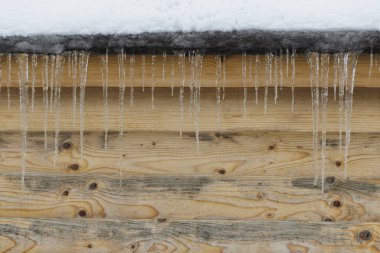 Buz sarkıtları kahverengi ahşap duvar bir arka plan üzerinde. Önden görünüm. Metin için yer.