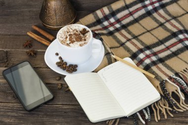 Kahverengi ahşap bir masa kapuçino, smartphone ve kahve tencere bardak. Sabah planlama