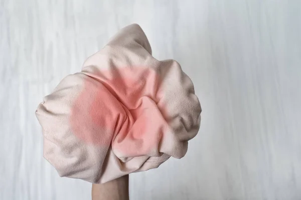 Crumpled clothes with a stain in a female hand. Close-up