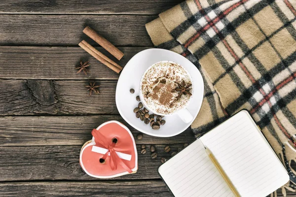 Fincan kapuçino, kalp şekilli kurabiye genişliği mesaj, defter ve kahverengi ahşap bir masa üzerinde kareli ekose. Tatil planlama