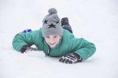 Karnına ve gülümsüyor karda içinde yatan çocuk. Portre yakın çekim.