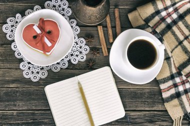 Kahve, kalp kurabiye kahverengi ahşap bir masa üzerinde mesaj, defter, kalem ve kahve Demlikli şeklinde. Tatil planlama