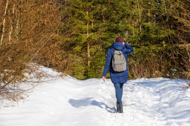 Karlı bir ormandaki bir sırt çantası konumu olan kız. Kış güneşli gün
