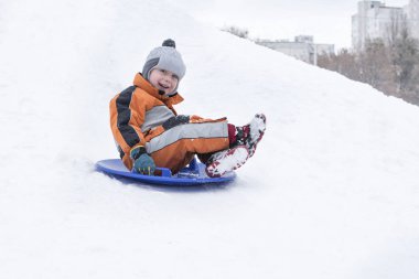 Mutlu küçük çocuk slaytlar kar daire üstünde belgili tanımlık tepe aşağı gülüyor. Mevsimlik kavramı. Kış günü