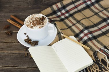 Fincan kapuçino ve defter ve kahverengi ahşap bir masa üzerinde kareli ekose. Planlama kavramı.