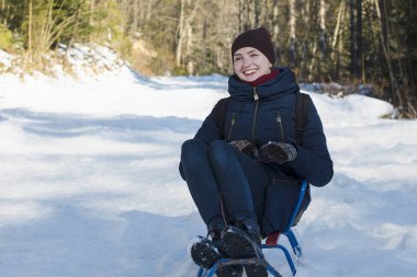 Gülen kız küçük bir kızak sürmek. Kış güneşli gün.