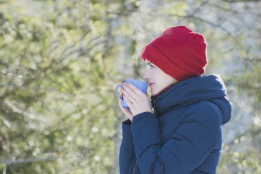 Kırmızı bir şapka ve onun el daimi yeşil arka planı bir kupa kızı. Portre. Yakın çekim