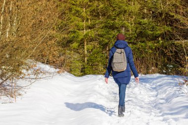Karlı bir ormanda yürüyüş sırt çantası olan kız. Kış güneşli gün