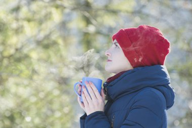 Kırmızı bir şapka ve onun el daimi yeşil arka planı bir kupa kızı. Portre. Yakın çekim