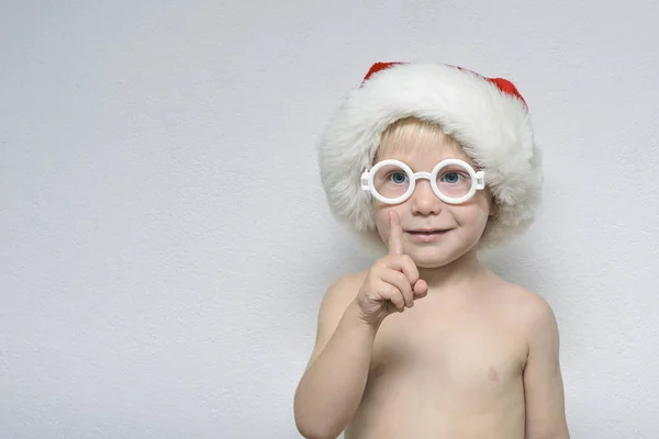 Mały Chłopiec Okularów Czapkę Mikołaja Stoi Jasnym Tle Portret — Zdjęcie stockowe