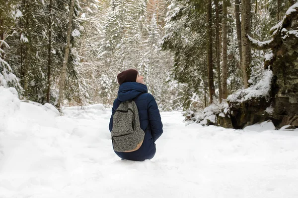 女孩背着背包坐在白雪覆盖的针叶林里 冬季多云 — 图库照片