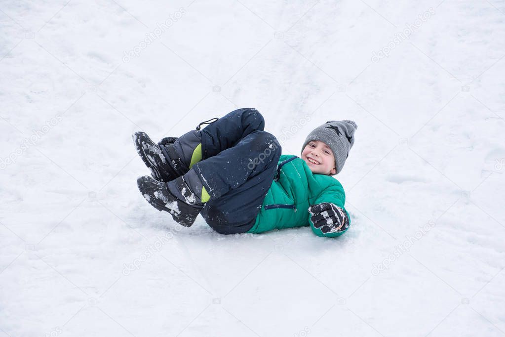 Boy falls rolling down a snowy hill. Winter games.