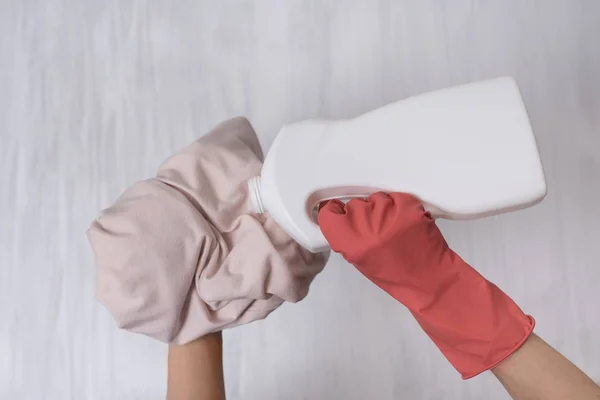 Hand in glove pours liquid for washing on clothes. Close-up