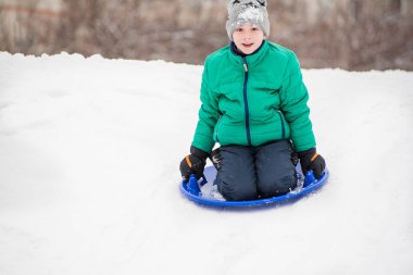 Mutlu çocuk slaytlar kar daire üstünde belgili tanımlık tepe aşağı. Mevsimlik kavramı. Kış günü.
