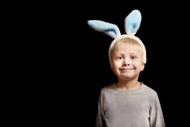 Tavşan'ın kulakları bir siyah arka plan üzerinde duran sevimli küçük sarışın çocuk. Portre. Kopya alanı.