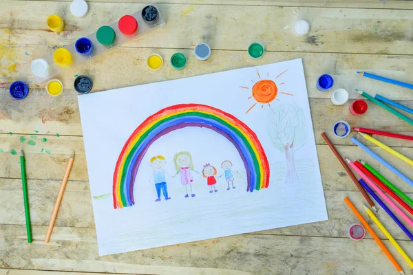 幸せな家族の概念 木製のテーブルの描画 男の子と女の子は虹と晴れた空の背景に手を握る — ストック写真