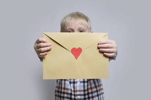 Blond Jongetje Houdt Een Envelop Met Hart Lichte Achtergrond — Stockfoto