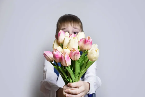 Jongetje Wit Overhemd Geeft Een Boeket Tulpen Lichte Achtergrond — Stockfoto