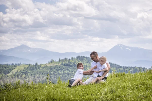 Heureux Père Avec Ses Deux Jeunes Fils Assis Sur Herbe Images De Stock Libres De Droits