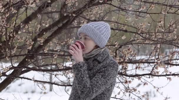 女孩正在一棵开花树旁喝咖啡 — 图库视频影像