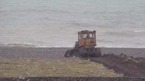 Buldozer Pracuje Posílení Pobřeží Proti Pozadí Rozbouřeného Moře Převážně Oblačno — Stock video