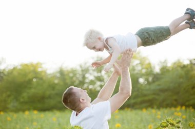 Babası bir yeşil ayçiçekleri alanı gökyüzüne karşı küçük gülen oğlu kadar atar